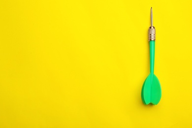 Photo of Green dart arrow on yellow background, top view with space for text