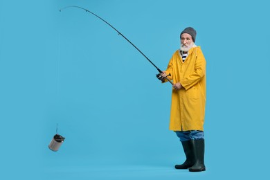Photo of Fisherman with fishing rod and tin can on light blue background, space for text