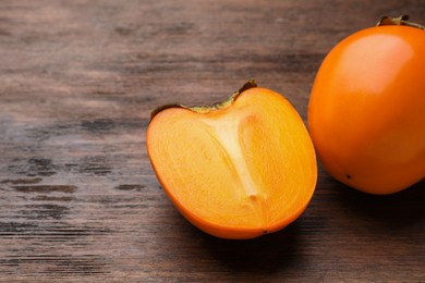 Photo of Delicious ripe persimmons on wooden table, space for text