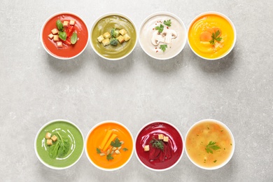 Photo of Various cream soups in bowls and space for text on grey background, top view