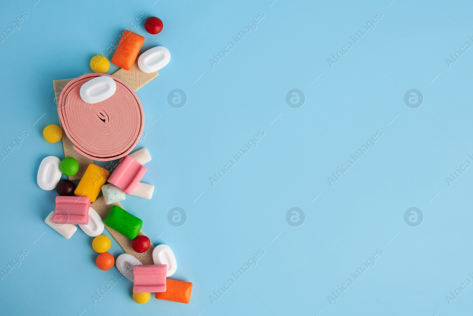 Photo of Many different chewing gums on light blue background, flat lay. Space for text