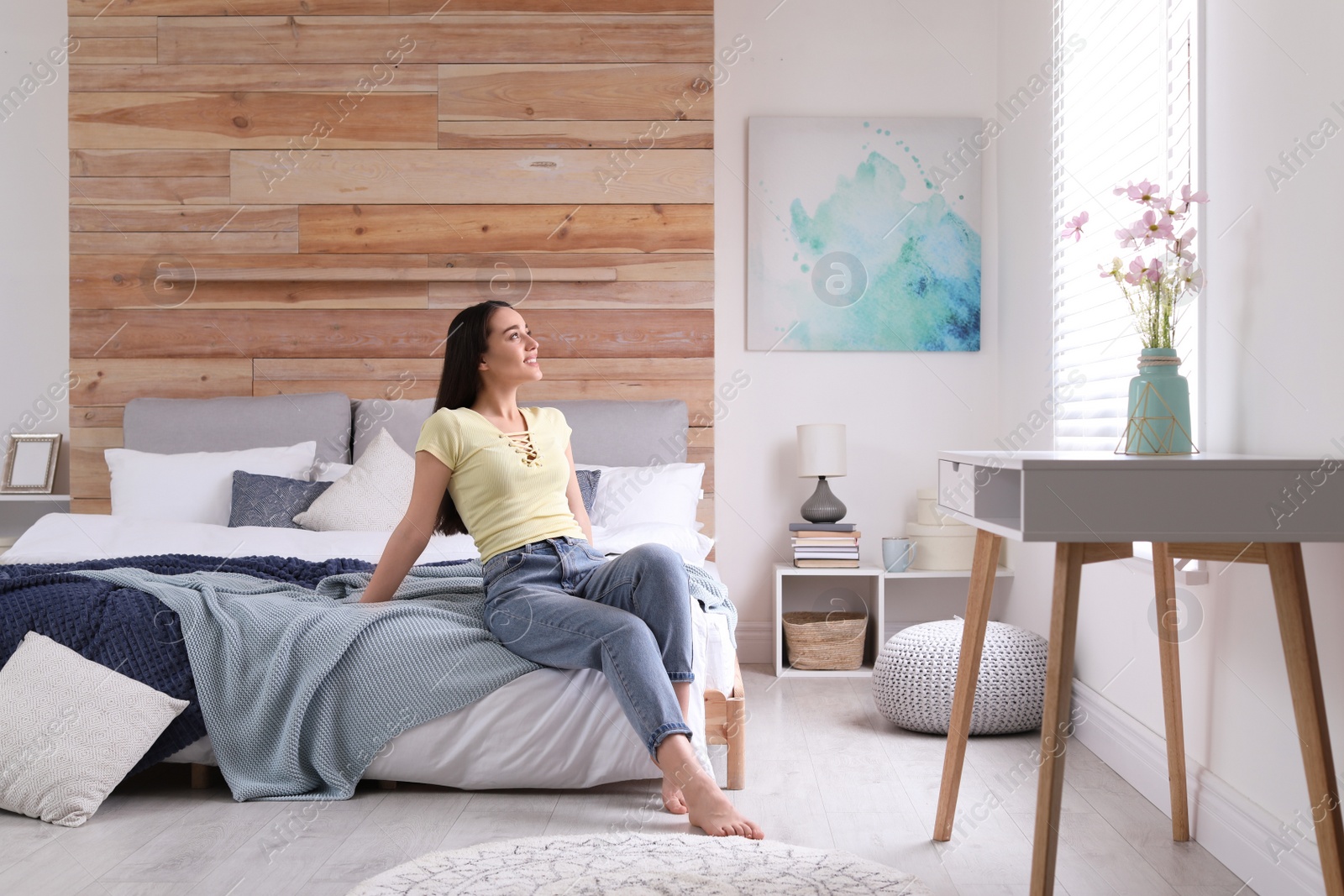Photo of Woman sitting on bed in modern room. Elegant interior