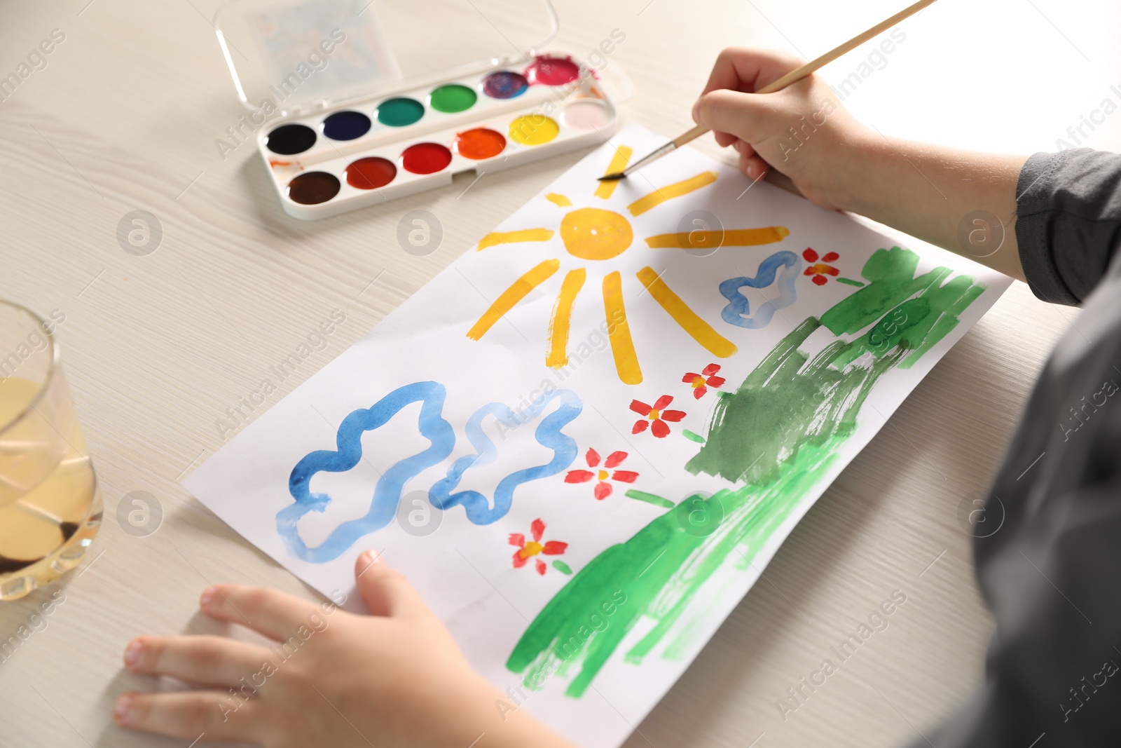 Photo of Little boy drawing picture at wooden table, closeup. Child`s art