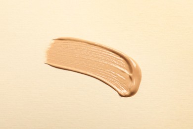 Smear of skin foundation on beige background, top view