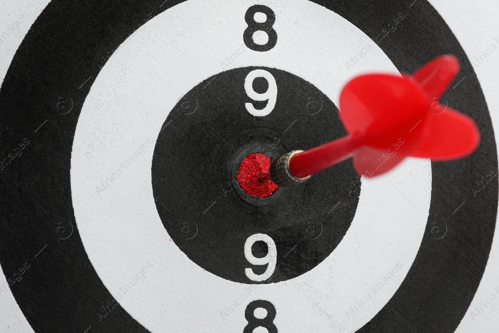 Photo of Dart board with color arrow hitting target, closeup