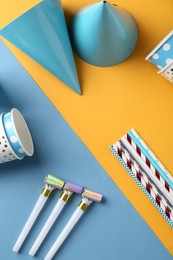 Photo of Party hats and other bright decor on color background, flat lay