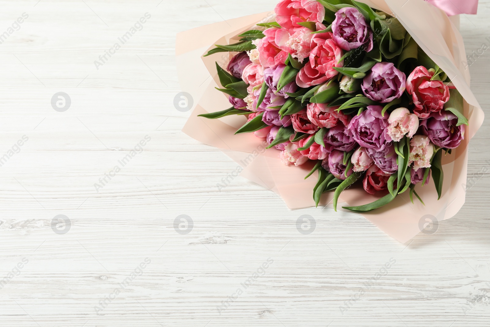 Photo of Bouquet of beautiful tulips on white wooden table, closeup. Space for text