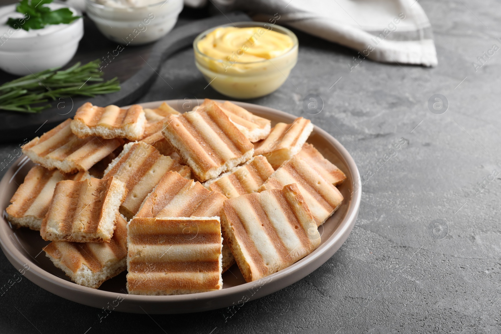 Photo of Delicious pita chips and sauce on grey table