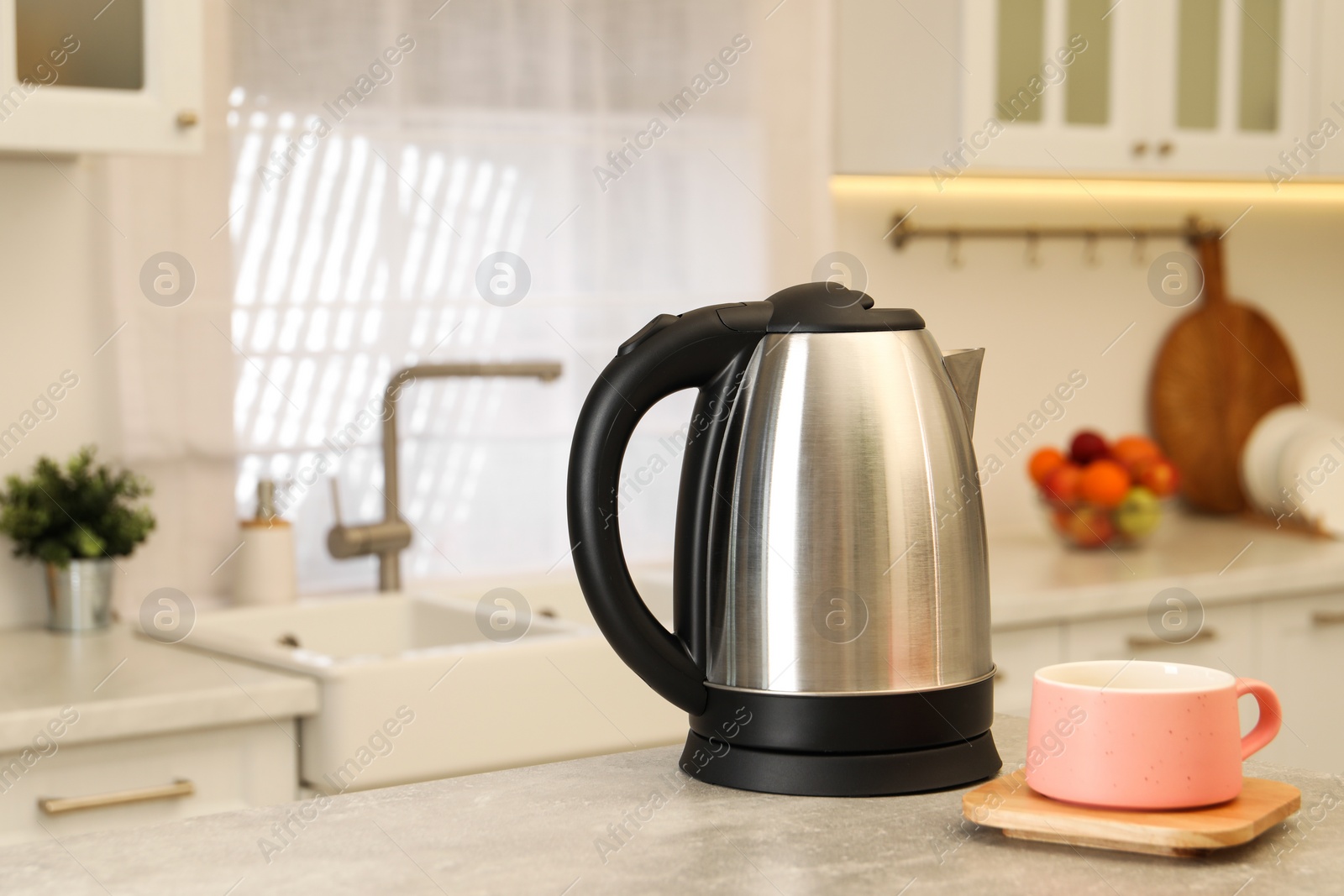 Photo of Electric kettle and cup on table in kitchen. Space for text