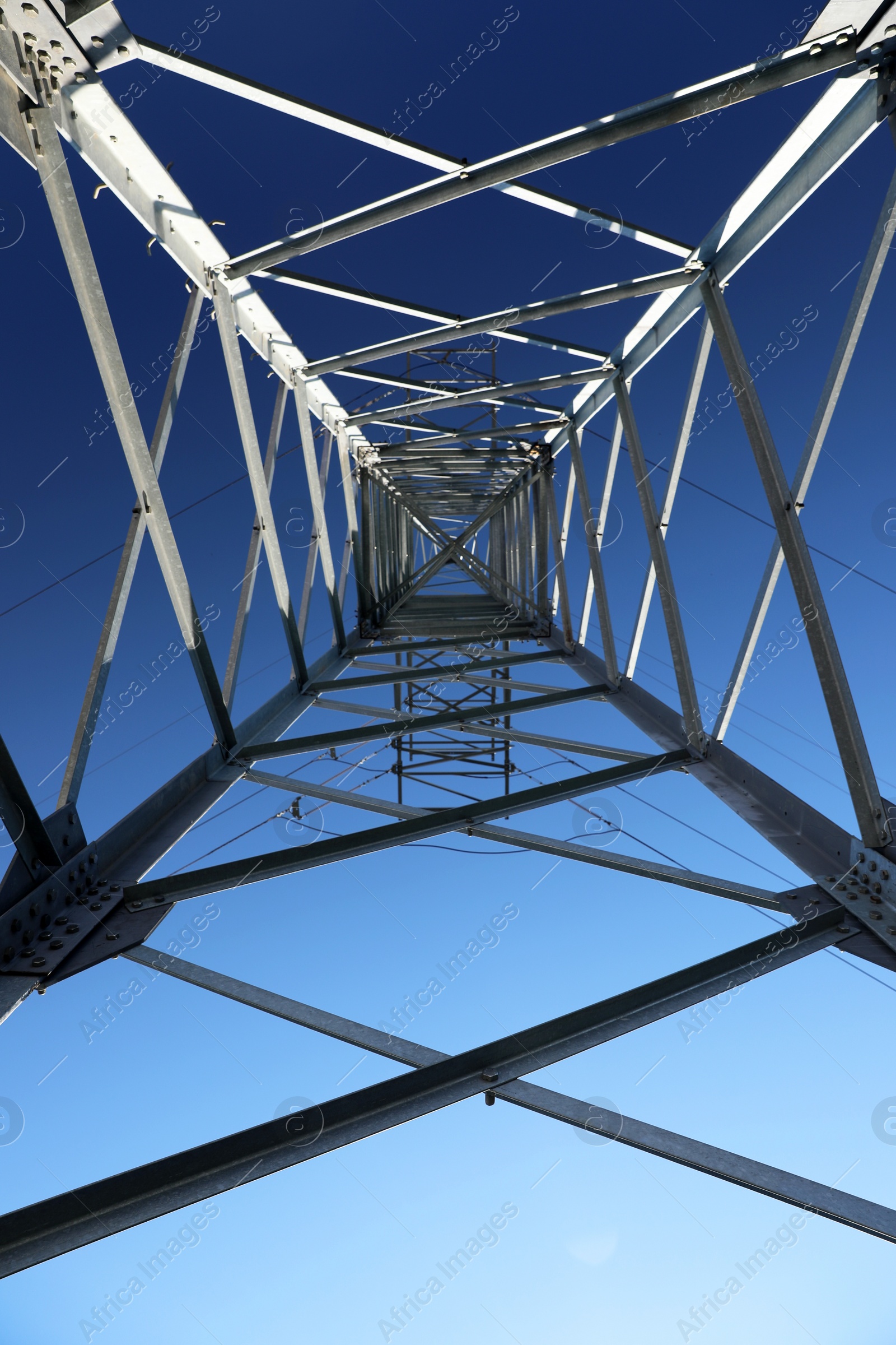 Photo of Modern high voltage tower against blue sky, bottom view