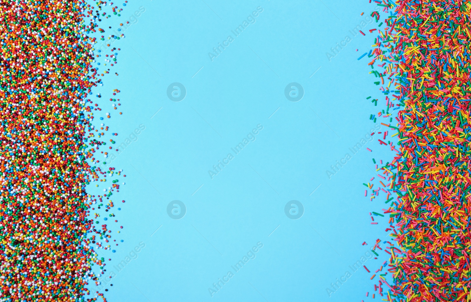 Photo of Colorful sprinkles on light blue background, flat lay with space for text. Confectionery decor