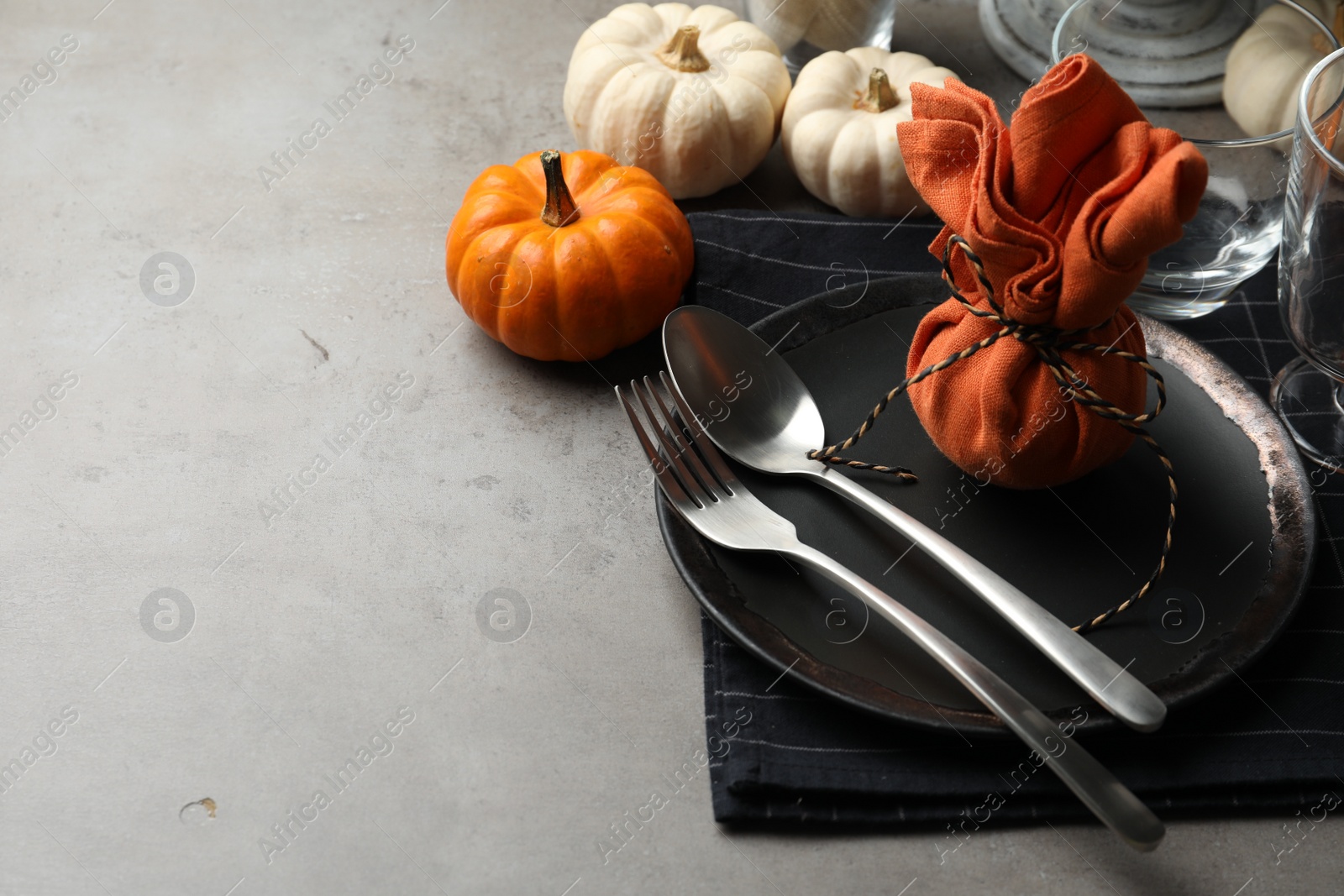 Photo of Seasonal table setting with pumpkins and autumn leaves on grey background. Space for text