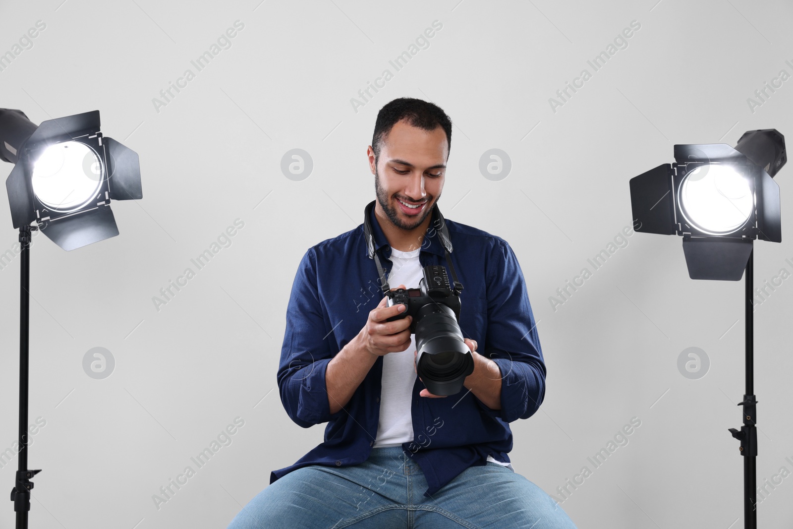 Photo of Young professional photographer with camera in modern photo studio