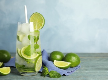 Delicious mojito and ingredients on blue wooden table. Space for text