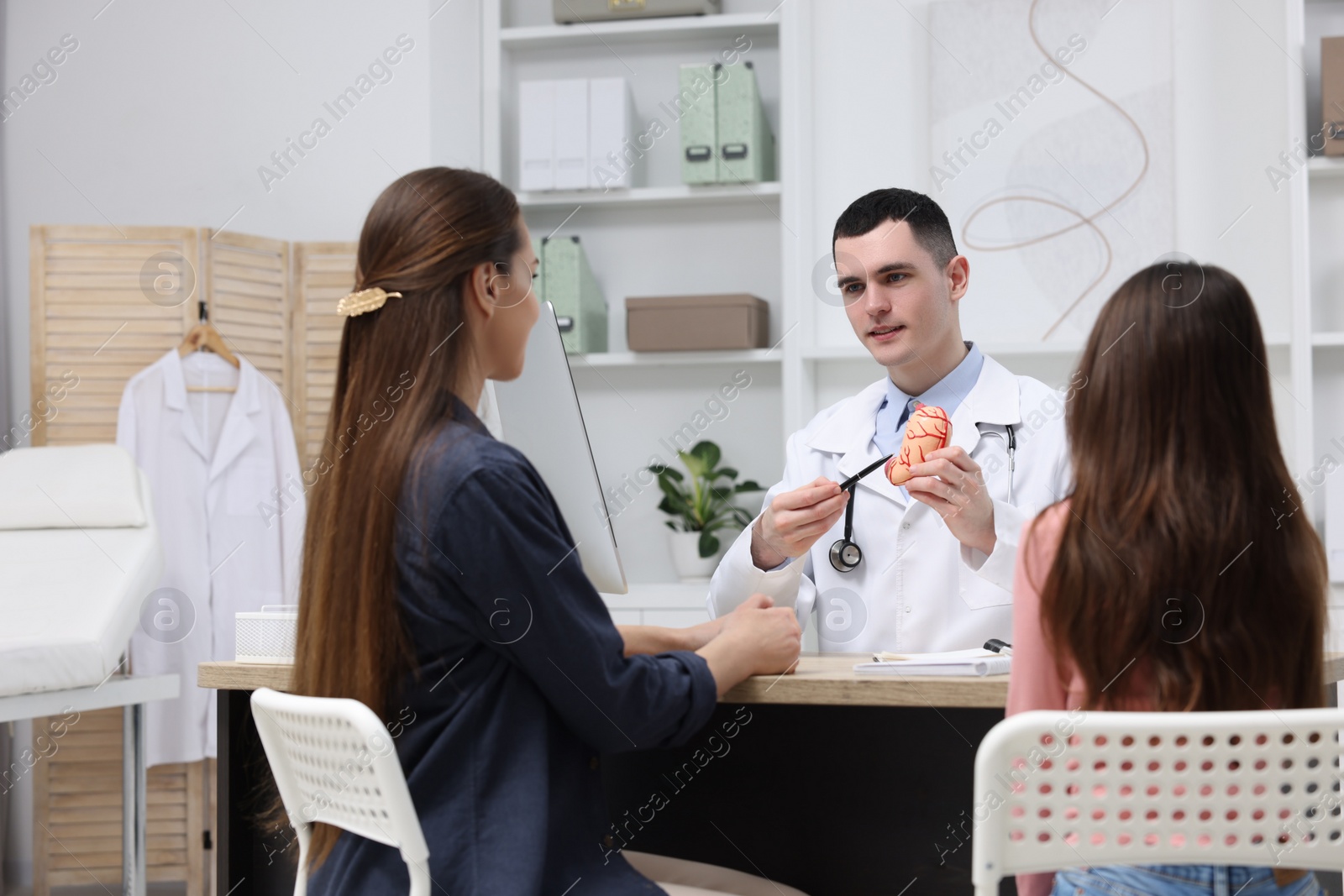 Photo of Gastroenterologist with model of stomach consulting woman and her daughter in clinic