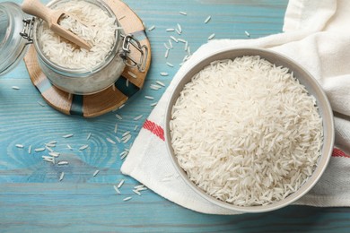 Photo of Raw basmati rice in bowl and jar on light blue wooden table, flat lay