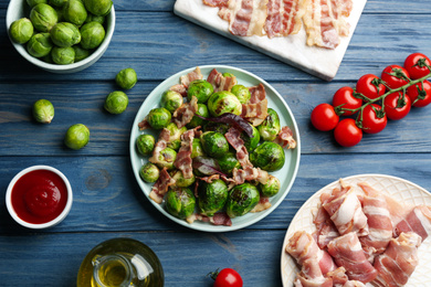 Delicious Brussels sprouts with bacon on blue wooden table, flat lay