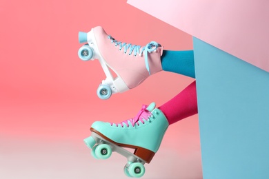 Woman with vintage roller skates on color background, closeup