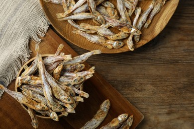 Photo of Delicious dried anchovies on wooden table, flat lay