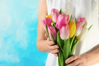 Photo of Girl holding bouquet of beautiful spring tulips on color background, closeup with space for text. International Women's Day