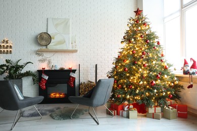 Photo of Beautiful Christmas tree near fireplace and cosy armchairs in room. Interior design