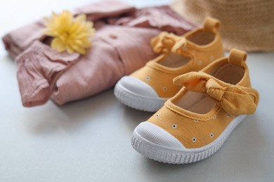 Photo of Stylish child shoes and clothes on grey background, closeup
