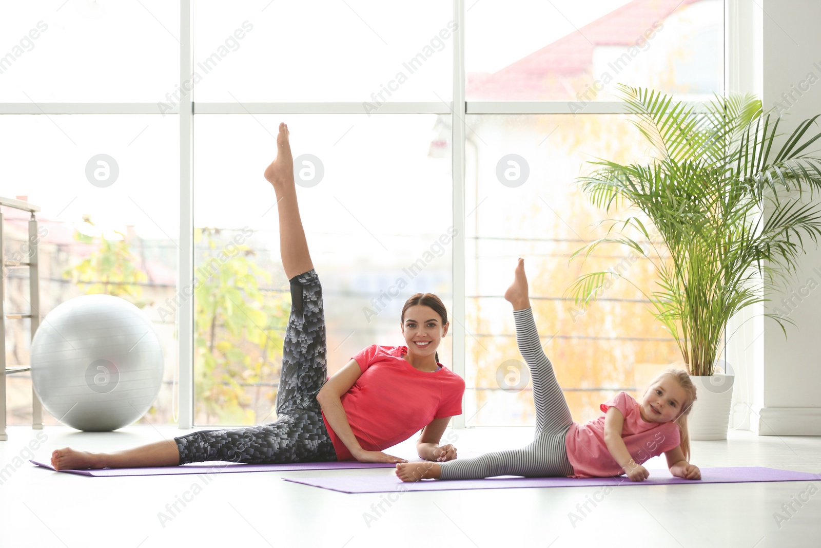 Photo of Woman and daughter doing yoga together at home. Fitness lifestyle