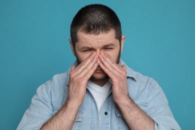 Man suffering from headache on light blue background