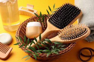 Photo of Wooden brushes and different hair products on orange background
