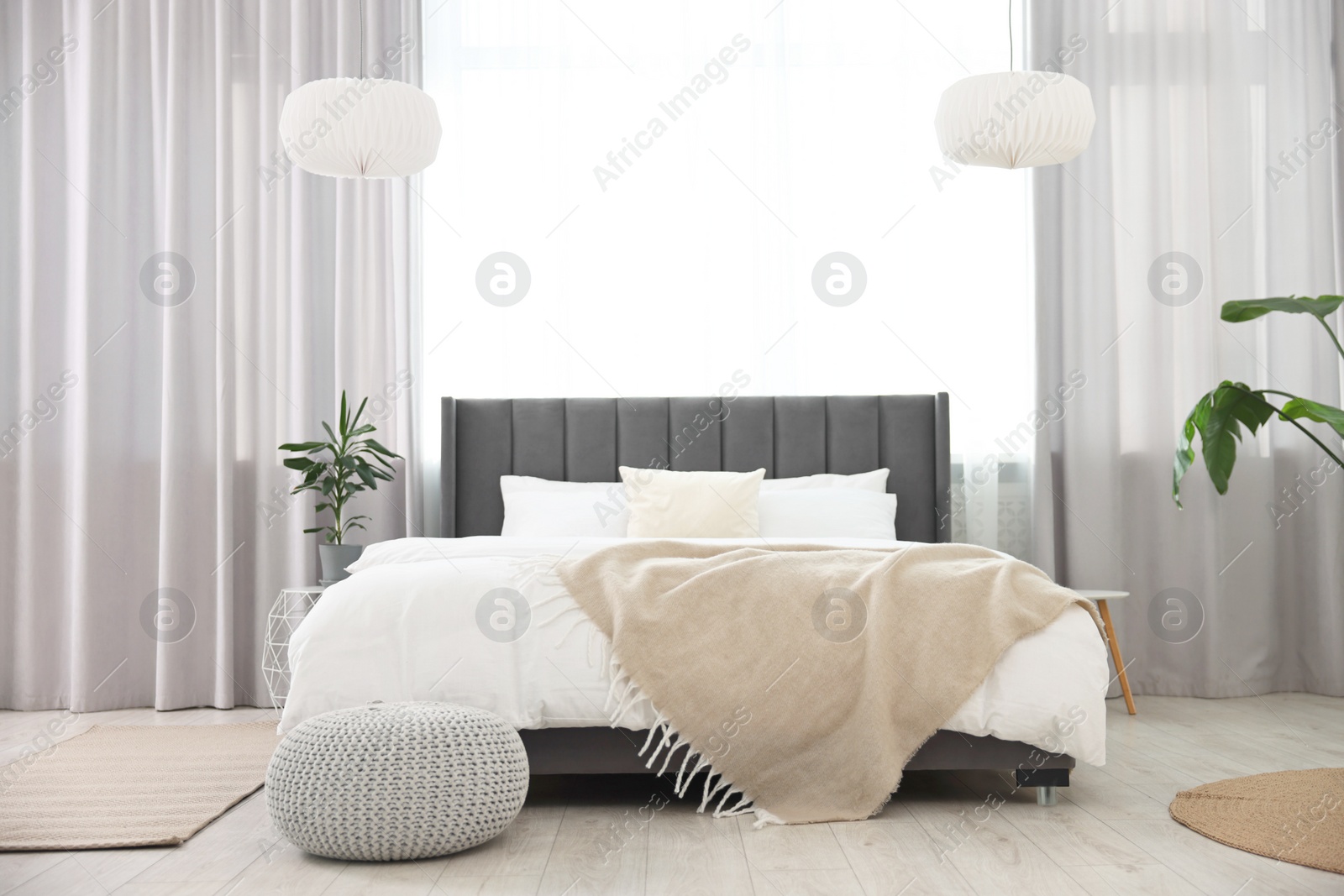 Photo of Soft beige plaid on bed in stylish bedroom. Interior design