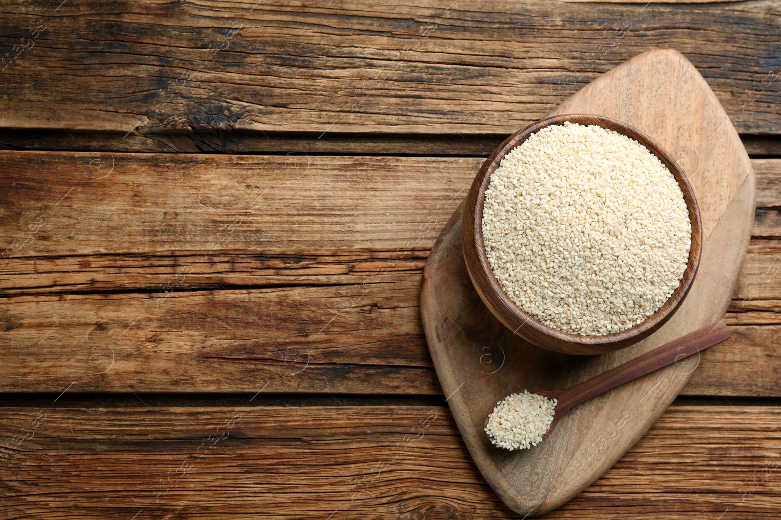 Photo of White sesame seeds on wooden table, top view. Space for text