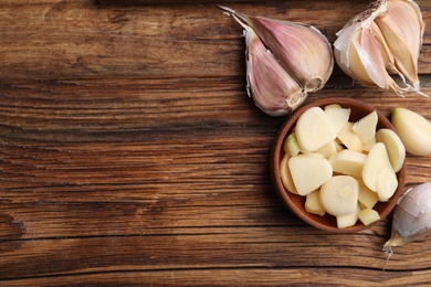 Photo of Fresh organic garlic on wooden table, flat lay. Space for text