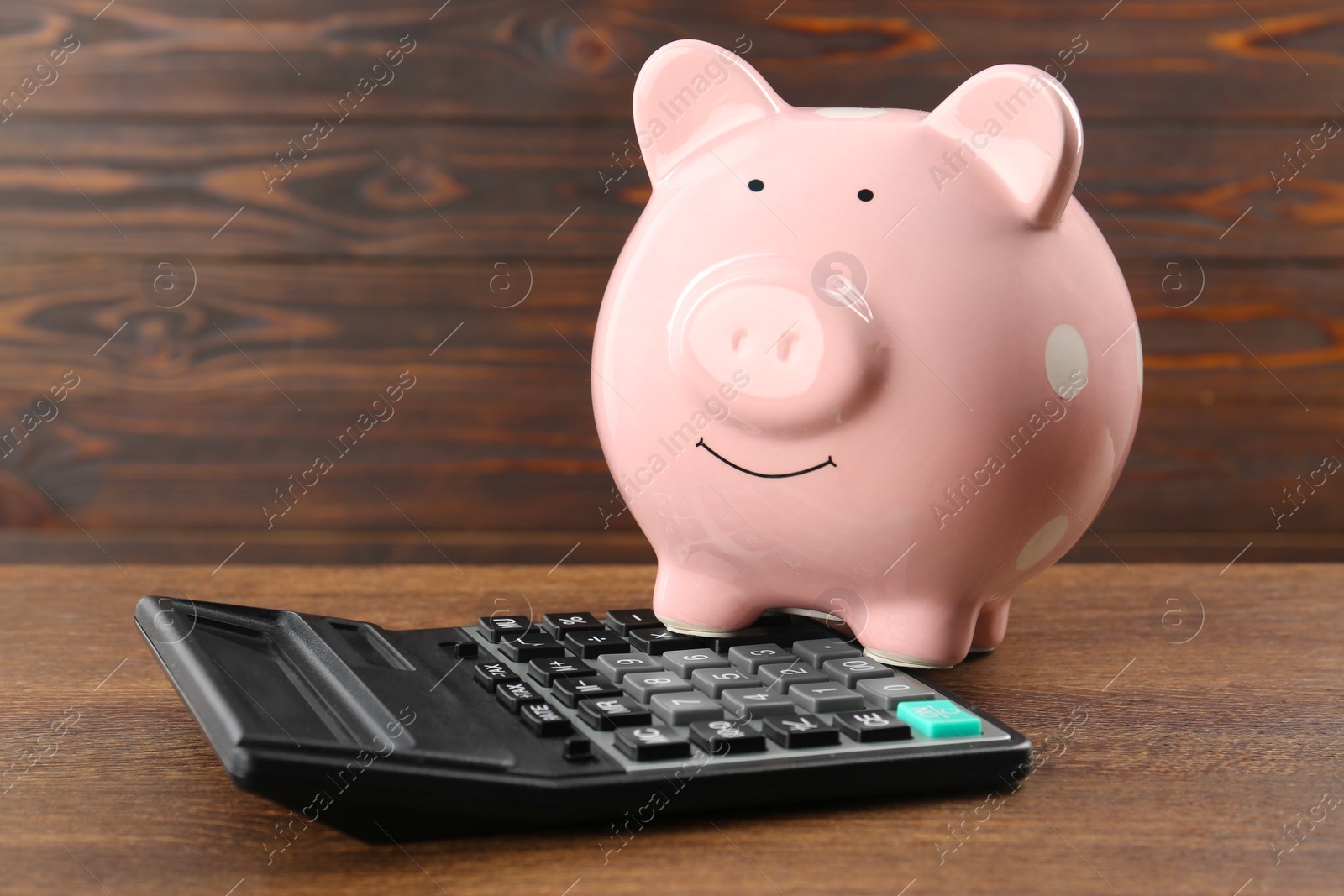 Photo of Calculator and piggy bank on wooden table