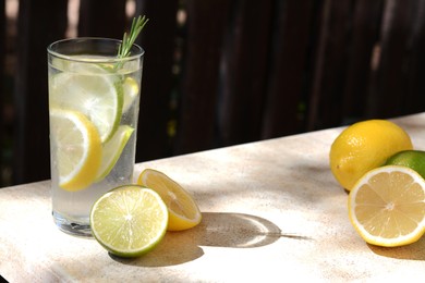 Photo of Summer refreshing lemonade and ingredients on light table outdoors, space for text