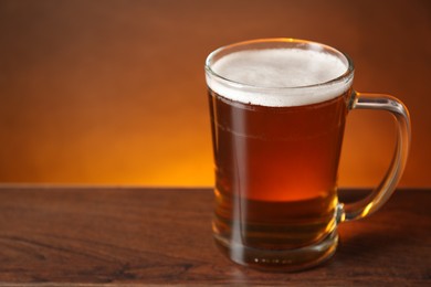 Mug with fresh beer on wooden table against color background, closeup. Space for text