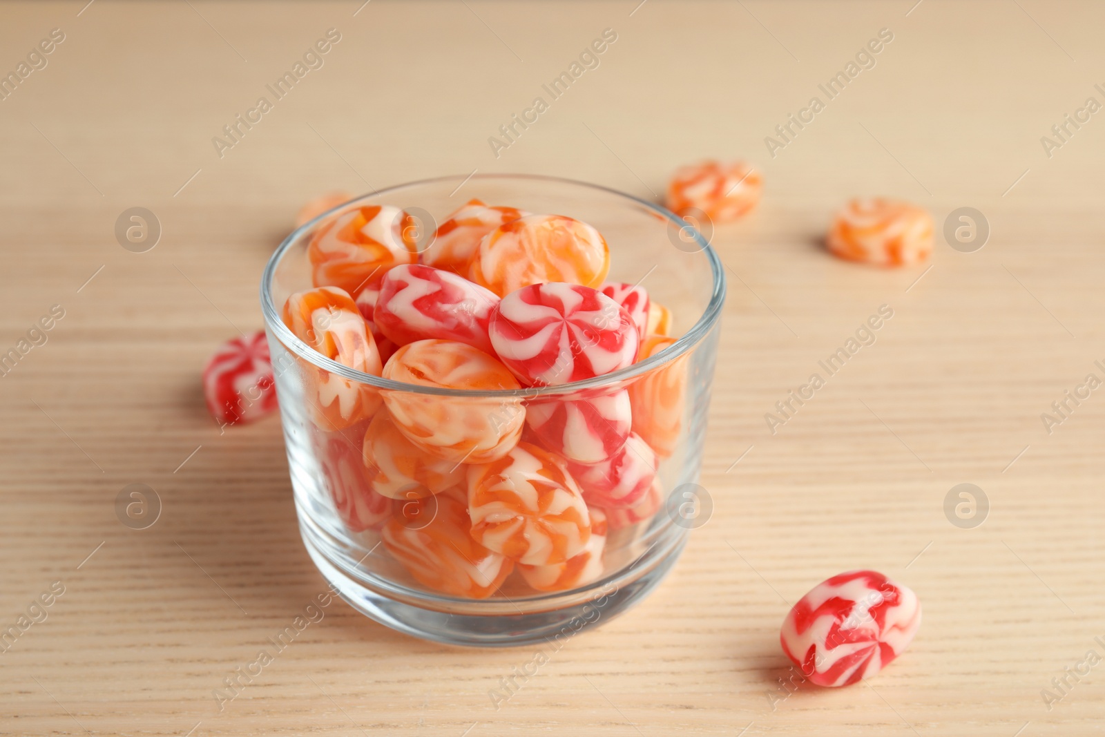 Photo of Glass with delicious colorful candies on wooden table