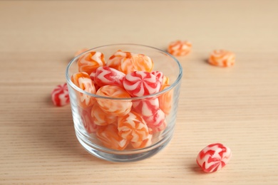 Glass with delicious colorful candies on wooden table