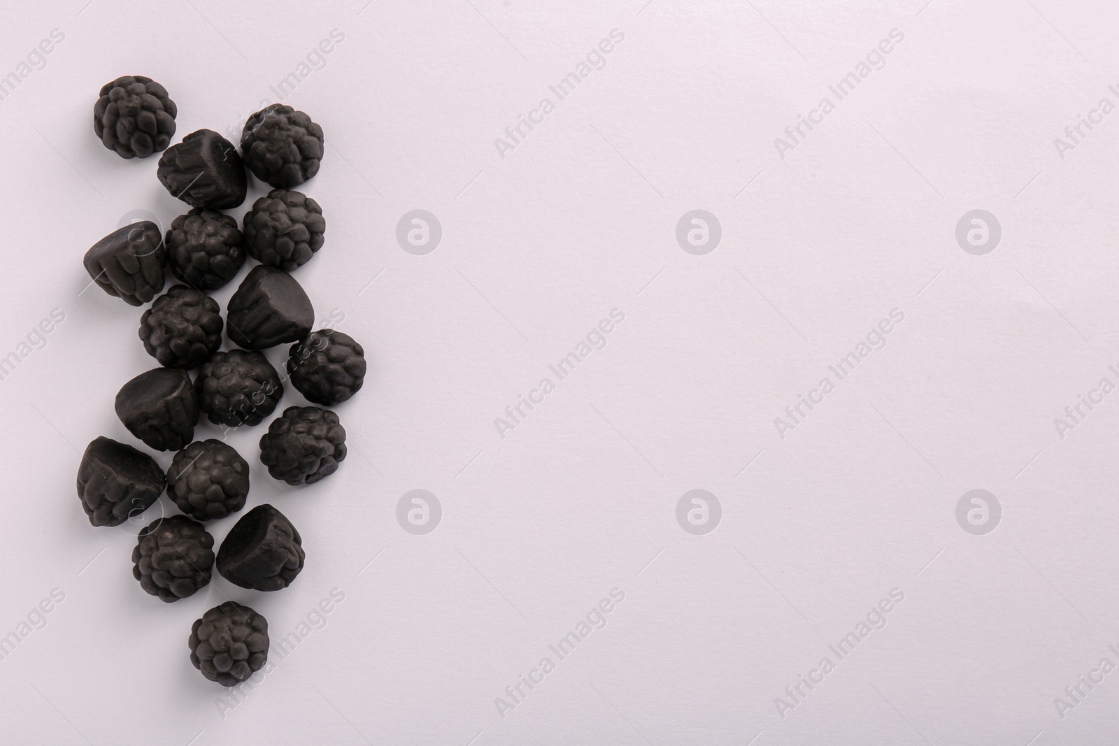 Photo of Tasty liquorice candies on light background, top view. Space for text