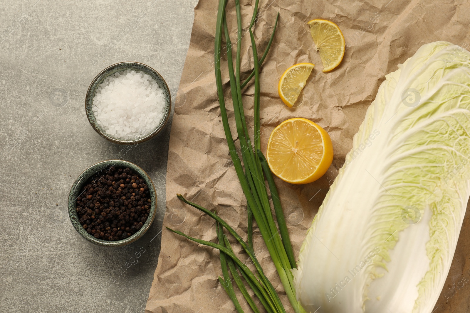 Photo of Fresh Chinese cabbage, lemon, green onion and spices on light grey table, flat lay