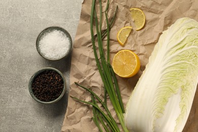 Photo of Fresh Chinese cabbage, lemon, green onion and spices on light grey table, flat lay