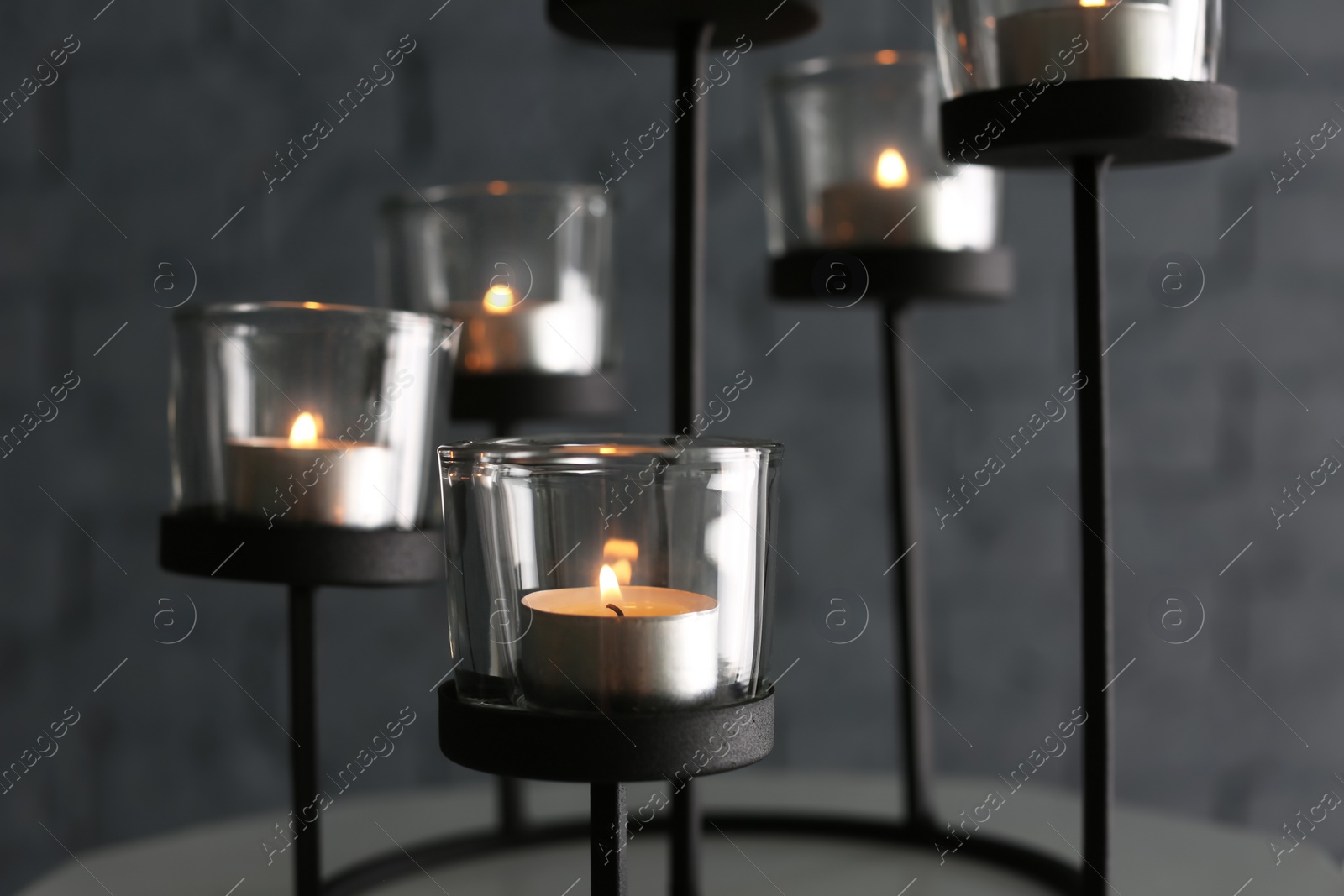 Photo of Burning candles in holders against blurred background, closeup