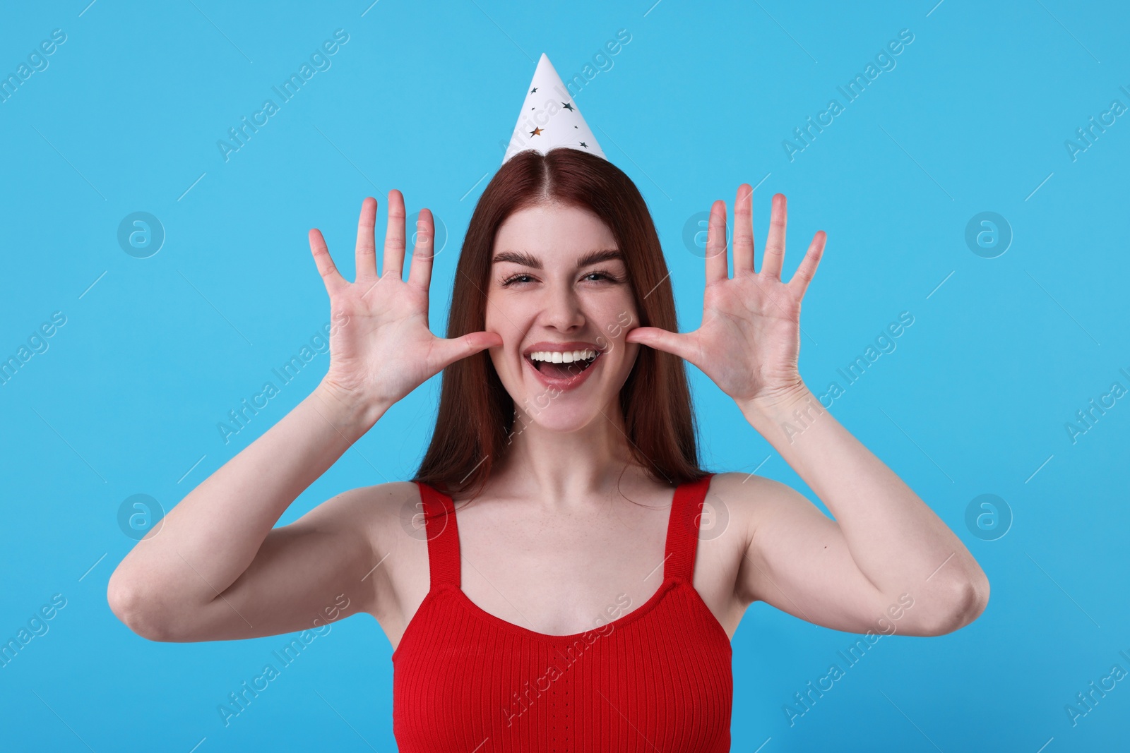 Photo of Happy woman in party hat on light blue background