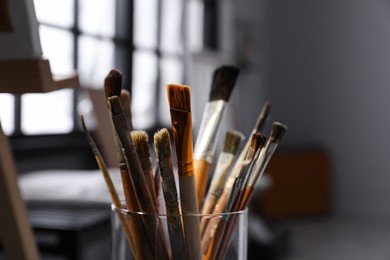Photo of Holder with different brushes in artist's studio, closeup