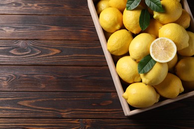 Photo of Fresh lemons in crate on wooden table, top view. Space for text