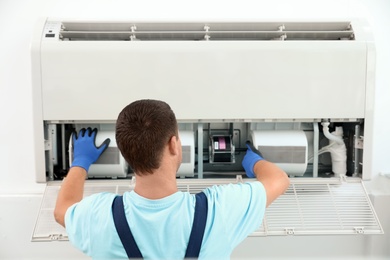 Photo of Technician installing and checking air conditioner indoors