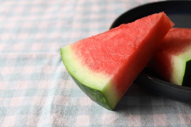 Photo of Sliced fresh juicy watermelon on checkered light blue tablecloth, closeup