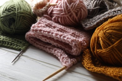 Photo of Balls of soft yarns, knitting and needles on white wooden table