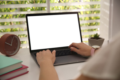 Photo of Woman working with modern laptop at white table, closeup. Space for design