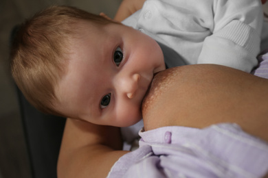 Photo of Young woman breast feeding her little baby at home, closeup