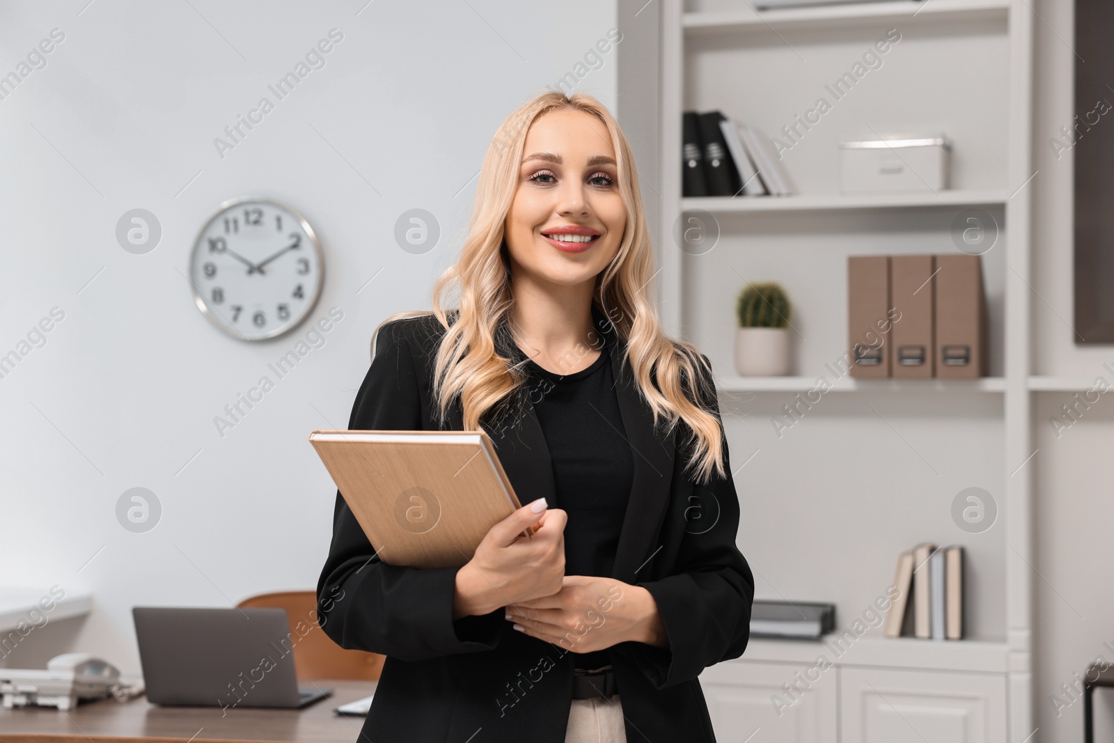 Photo of Portrait of happy secretary with notebook in office